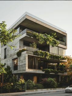 a car driving past a tall building with plants growing on it's windows and balconies