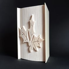 an intricately carved book with leaves on the front and back cover, is shown