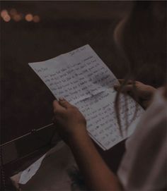 a person holding a piece of paper and writing on it with a pen in their hand