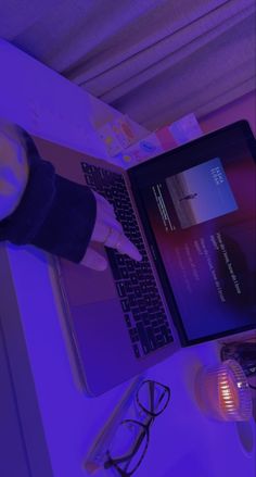 a laptop computer sitting on top of a desk next to a person's hand