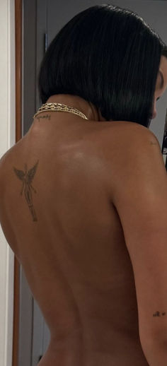 a woman with tattoos on her back looking in the mirror