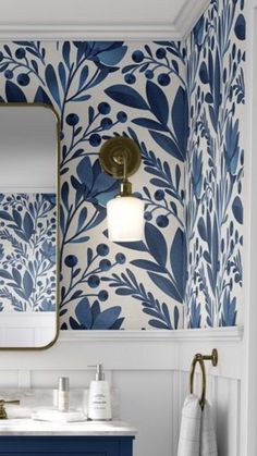 a bathroom with blue and white wallpaper, gold fixtures and a large mirror over the sink