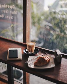 a table with a plate of food and a cup of coffee on it next to a window