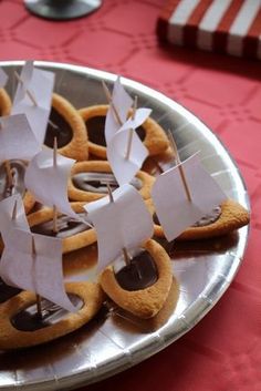 some cookies are on a silver plate with white paper boats