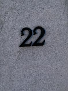 the number twenty two is written in black on a stucco wall