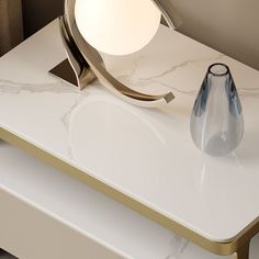 a white table with a glass vase on it and a light that is on top