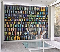 there is a glass table in front of a wall full of colorful vases on display