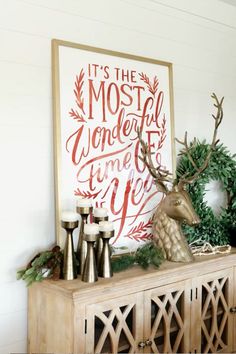 a wooden cabinet with christmas decorations on top and a deer head in the corner next to it