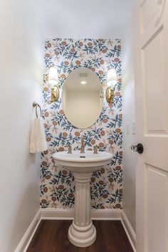 a white pedestal sink sitting under a bathroom mirror