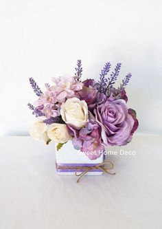 a bouquet of purple and white flowers in a square vase