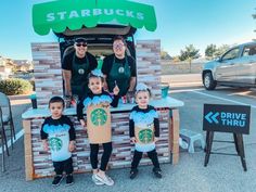 some people and two children are standing in front of a food cart that has starbuckss on it