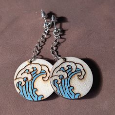 These stunning earrings capture the power and beauty of the ocean with a bold wave design. Crafted from high-quality wood, each pair features intricate blue wave details that are sure to catch the eye. The 30mm x 30mm circular design adds a touch of modern elegance, while the delicate chain adds a playful element. Perfect for: Beach days and summer adventures Gifts for holidays, birthdays, or special events Nautical-themed outfits Everyday wear to add a touch of coastal charm Dimensions: 30mm x 30mm x 3mm Material: Wood Note: Due to the natural variations in wood, the color and grain may vary slightly from the image. Ocean-inspired Drop Earrings Gift, Ocean-inspired Drop Earrings, Ocean Wave Earrings, Ocean-inspired Dangle Single Earring, Ocean-inspired Dangle Hoop Earrings For Beach, Adventure Gifts, Wave Design, Blue Waves, Dangly Earrings