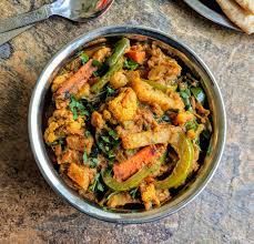 a bowl full of food sitting on top of a table next to a plate with bread