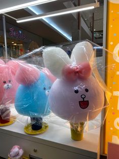 three stuffed animals are on display in a store window with plastic wrap around their heads