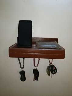 a cell phone is sitting on top of a shelf with keys and wallets attached to it