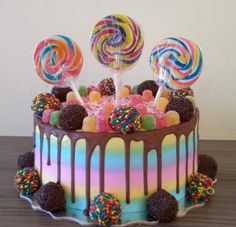 a cake with lots of candy and lollipops on top, sitting on a table