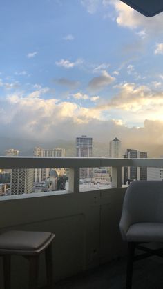 two chairs sitting on top of a balcony next to a tall building with buildings in the background