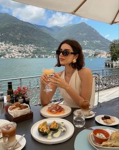 a woman sitting at a table with food and drinks