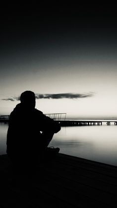 a person sitting on a dock looking at the water