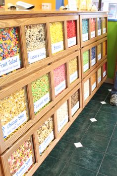 a display case filled with lots of different types of cereal in front of a green wall