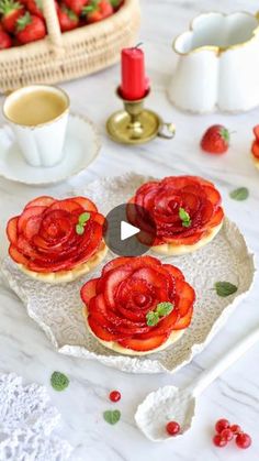 strawberry tarts on a plate with strawberries in the background and teacups to the side