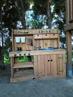 an outdoor kitchen made out of wood with pots and pans