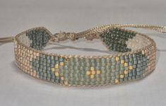 a close up of a bracelet on a white surface with gold and blue beads in it