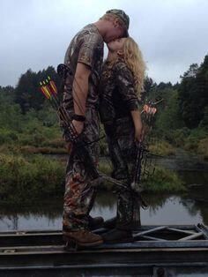 a man and woman kissing in the woods with bow'd arrows around their necks