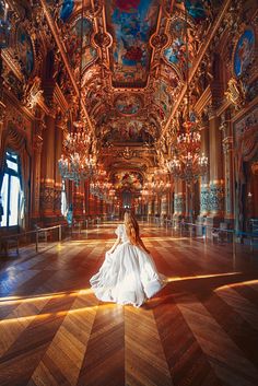 a woman in a white dress is sitting on the floor with chandeliers hanging from the ceiling