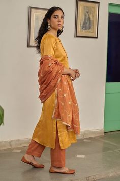 Warm yellow plain kurta. Paired with a pant. Comes along with a rust dupatta with hand embroidery and kiran lace border. - Aza Fashions Festival Tussar Silk Palazzo Set With Straight Kurta, Slub Silk Kurta With Dupatta For Puja, Diwali Tussar Silk Palazzo Set With Straight Kurta, Raw Silk Set With Dupatta For Puja, Tussar Silk Straight Kurta Sets For Festivals, Slub Silk Sharara With Dabka And Straight Kurta, Transitional Chanderi Churidar, Festival Tussar Silk Straight Kurta Sets, Raw Silk Churidar With Dupatta