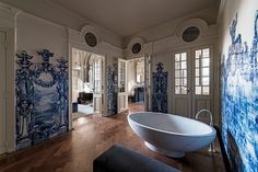 a large bathtub sitting in the middle of a room with blue and white wallpaper