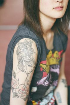 a woman with tattoos on her arm sitting down