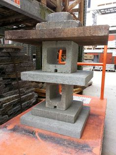 a large stone lantern sitting on top of a metal table next to stacks of bricks