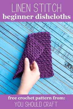 a hand holding a purple crochet dishcloth on top of a blue table