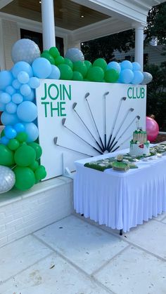 a table with balloons and a sign that says join the club on it in front of a building