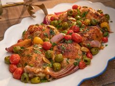 a white plate topped with meat and veggies on top of a wooden table