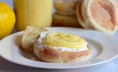 a plate topped with bread and butter next to two lemon juices on a table