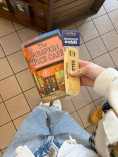 a person holding two books in their hands on the floor with tiled floors behind them