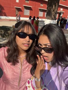 two women standing next to each other with sunglasses on