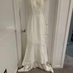 a white wedding dress hanging on a door