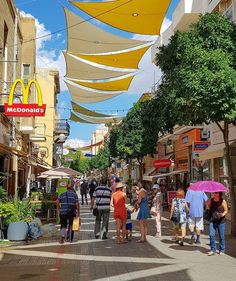 many people are walking down the street with umbrellas