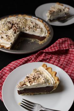 a piece of pie on a plate with a fork next to it and another slice in the background