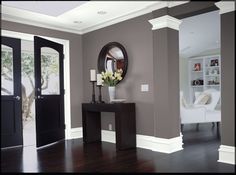 a living room with hardwood floors and gray walls, along with a mirror on the wall