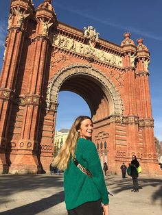 a woman is standing in front of an arch