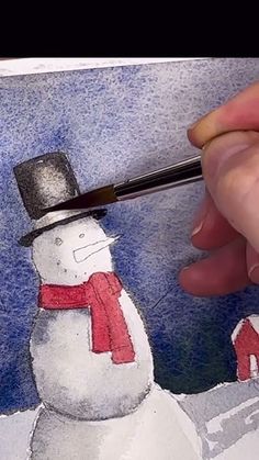 someone is painting a snowman with a brush and watercolor pencils on paper