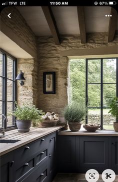 a kitchen with black cabinets and stone walls