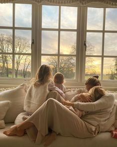 three women sitting on a couch in front of a window