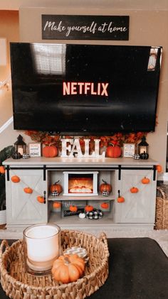 a television sitting on top of a tv stand next to a basket filled with pumpkins