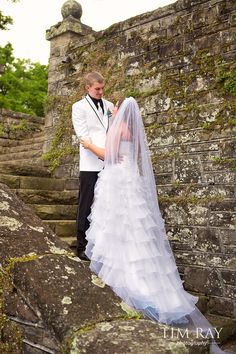 the bride and groom are standing on some steps together in front of an old stone wall