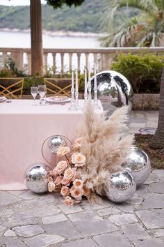 the table is set with silver balls and flowers